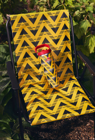 Yellow and black patterned chair with a red cup holder on a green leafy background
