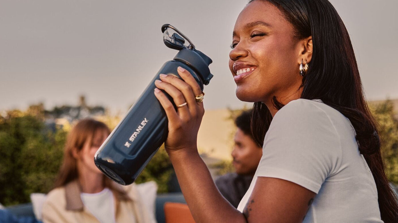 Woman holding a water bottle outdoors with friends in the background